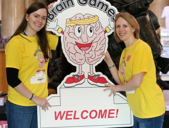 Brain Games volunteers in yellow t-shirts next to a cardboard cartoon brain